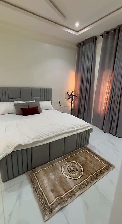Bedroom with grey bed, rug and floor-length curtains
