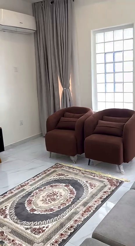 Sitting room with burgundy armchairs, grey curtains and a patterned rug
