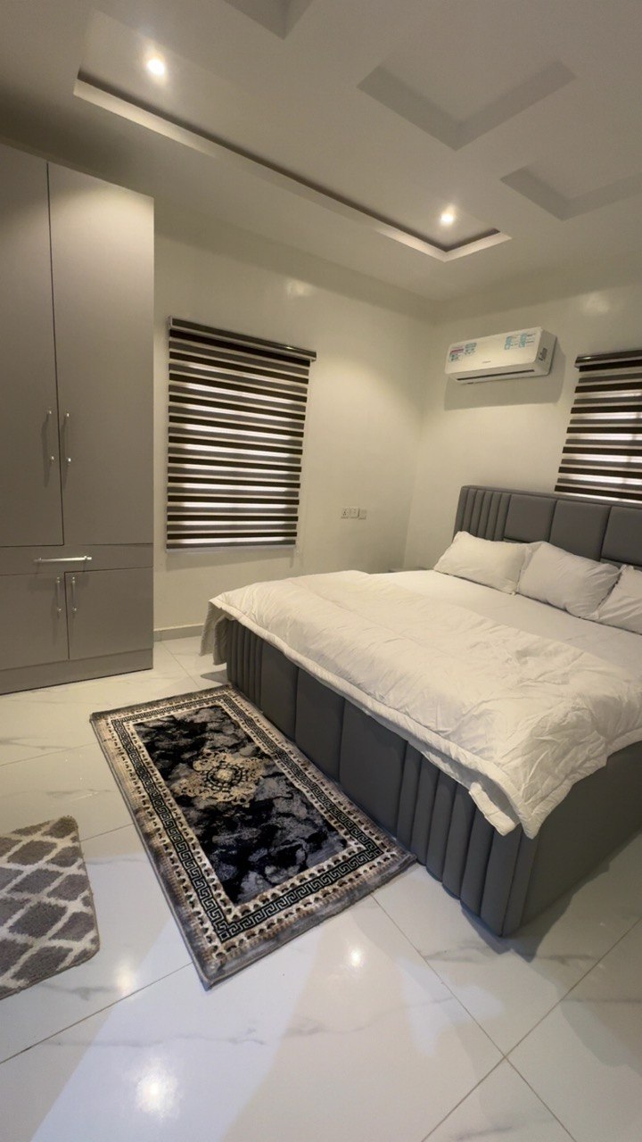 Bedroom with a grey upholstered bed and white linen